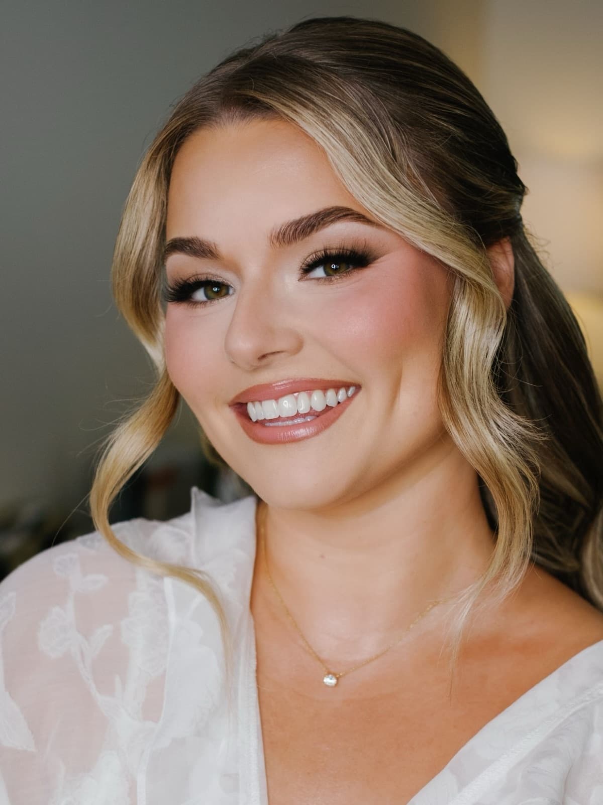 A smiling bride with soft waves and glowing bridal makeup